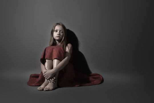 emotional Studio portrait of a child that depicts the suffering of a teenager on a gray background. Fifty percent black and white. symbolizes problems in the family, autism, depression