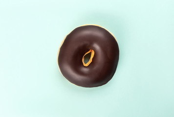 A chocolate tasty doughnut on turquoise background.