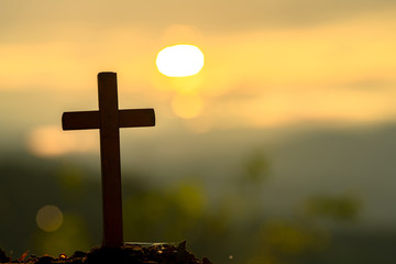 The silhouette of the cross across the mountain at sunset