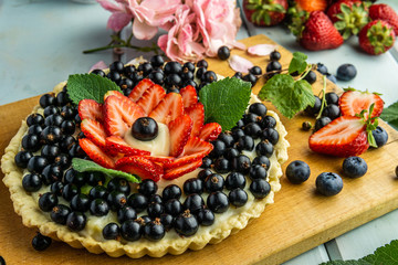 Cake with berries Pie with strawberries and black currants on blue rustic table.