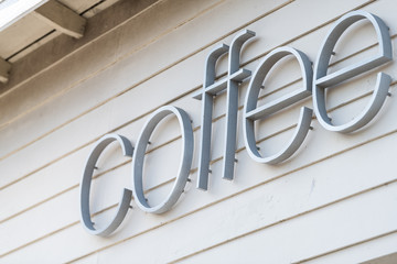 Generic text sign of coffee for coffeehouse shop on white building wall