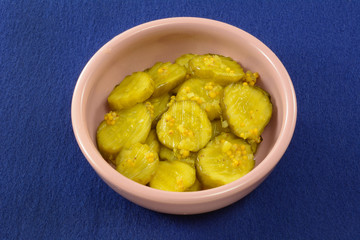 Sweet southern bread and butter pickles in pink condiment bowl on blue background