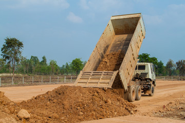 Fototapeta na wymiar Dump truck unloading soil or sand at construction site. Heavy machinery for earth work in construction industrial.
