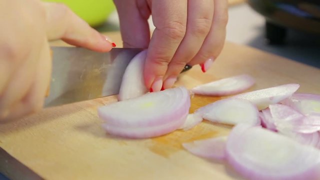 Woman knife red onions on a wooden board. Time laps