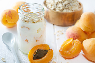 Oatmeal milkshake, smoothie or yogurt with fresh apricot on a white wooden table.