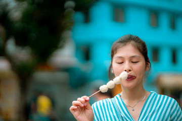 Asian young female eating famous street food - fish ball, in Hong Kong