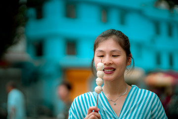 Asian young female eating famous street food - fish ball, in Hong Kong