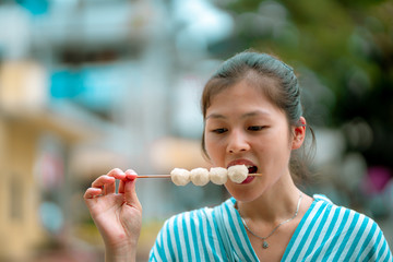 Asian young female eating famous street food - fish ball, in Hong Kong