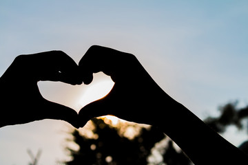 Fototapeta premium love shape hand silhouette at sunset