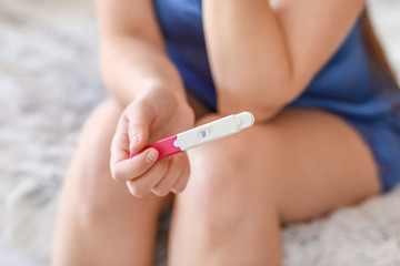 Obraz na płótnie Canvas Young woman with pregnancy test at home, closeup