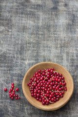 Fresh organic red currants in a wooden bowl on a dark wooden background, rustic style, top view, horizontal