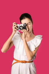 Young girl with photo camera on color background