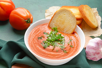 Bowl of tasty tomato cream soup and bread on table