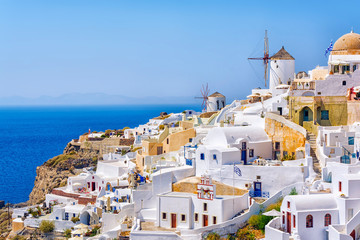 Traditional white architecture with windmills in greek picturesque Oia village on Santorini island,...