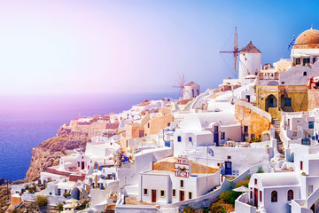 Traditional white architecture with windmills in greek picturesque Oia village on Santorini island,...
