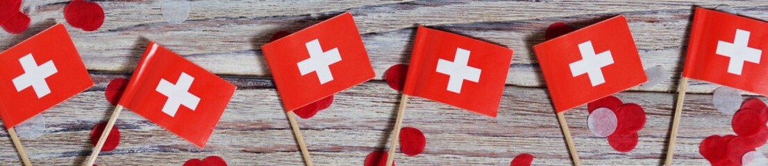 independence day Switzerland, August 1. Federal holiday in honor of the founding of the Swiss Confederation. day of the Confederacy. mini flags with confetti on wooden background. banner