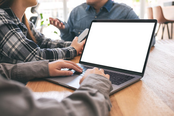 A woman using and typing at mockup laptop computer with friends in background