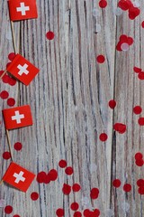independence day Switzerland, August 1. Federal holiday in honor of the founding of the Swiss Confederation. day of the Confederacy. mini flags with confetti on wooden background. vertical
