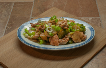 Oriental chicken with vegetables, onion, green pepers, and chopped chives on top, with a touch of soy sauce and ginger,.