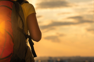 woman hiker in shorts and a t-shirt with a backpack on a sunset background