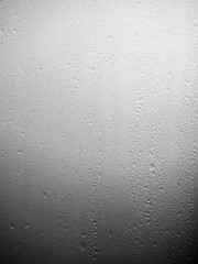 Vertical image of water drops, condens on white glass on a cold morning at sunrise.