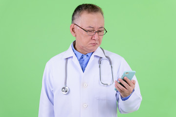 Mature Japanese man doctor with eyeglasses using phone
