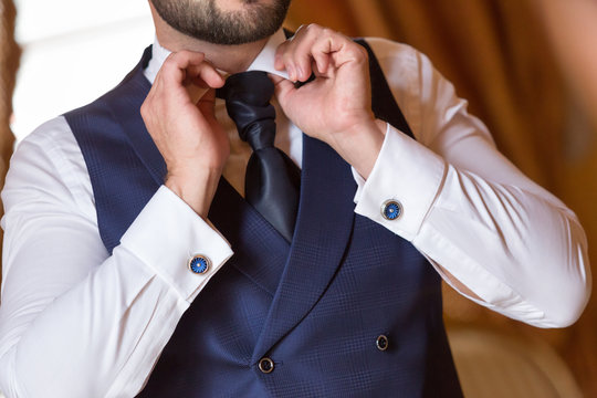 groom straightens shirt collar. Men's blue cufflinks on shirt cuff. Morning Groom Fees. The beginning of the wedding day. Blue men's vest. The original Blue men's tie.