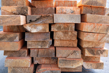 a pile of wooden planks lying on the street. wooden building material. A lot of wooden planks lying on the ground. Wooden sticks are lying on the ground. lumber lying on the street. Pine board cut