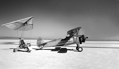Vintage motorized hang glider and small propeller plane on the surface of the salt lake. Mixed media