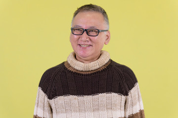 Face of happy mature Japanese man thinking ready for winter