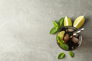 Glasse with cold cola and citrus on grey table, top view