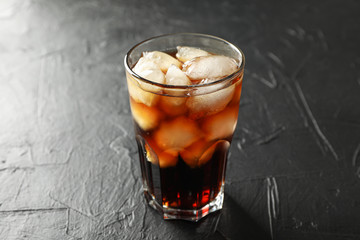 Glass of cold cola on black cement background