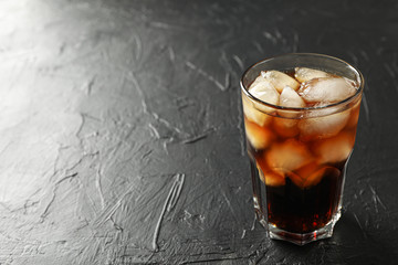 Glass of cold cola on black cement background