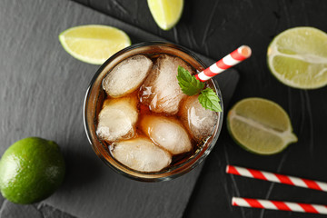 Glass with ice cola and tubule on black background with limes