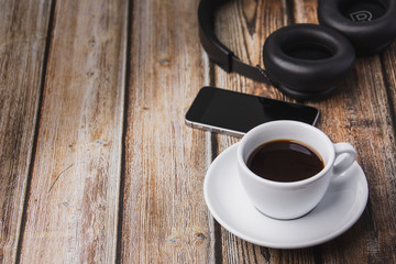 cup of coffee, headphones and mobile phones  on wooden table