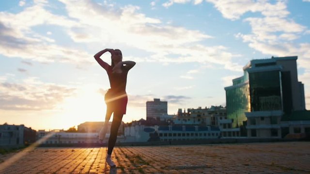 Young attractive woman in pointe jumps in ballet pas on the streets