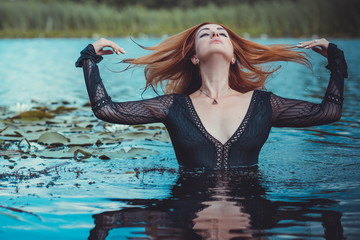 Sexy mystical woman in black bodysuit in water. Concept of femininity and sensual 