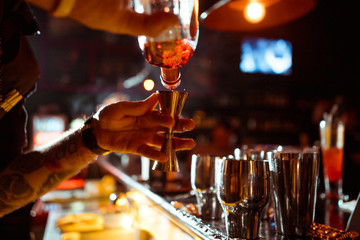 Expert barman is making cocktail at night club