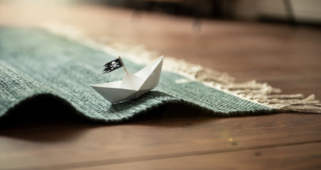 Paper Boat with Jolly Roger on Carpet Waves