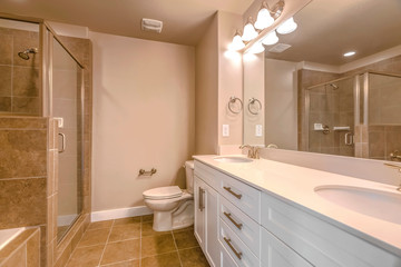 Vanity with double sink adjacent to the toilet inside a well lit bathroom