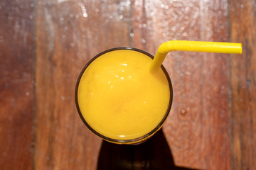 Mango smoothie in a glass on wooden background. Yellow mango shake. Tropical fruit concept . Top view, closeup