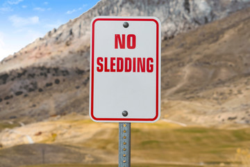 Close up of a No Sledding sign with a towering mountain in the background