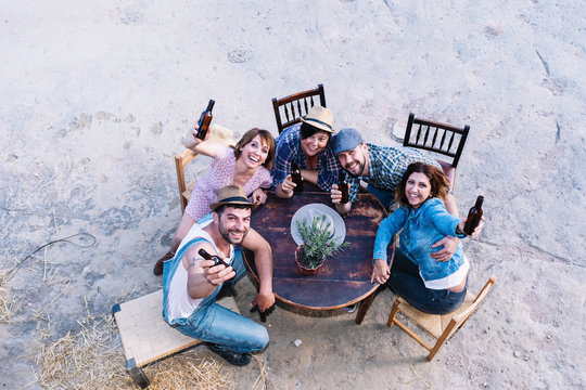 Aerial view of a group of friends sitting around a table holding beers
