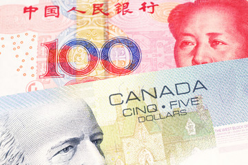 A close up macro shot of a blue five Canadian dollar bill with a one hundred yuan Chinese note 