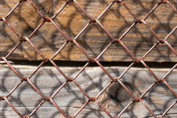 Old rusty metal mesh, vertical wooden planks beneath it