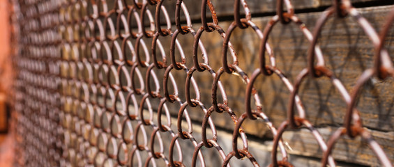 Old rusty metal mesh, vertical wooden planks beneath it