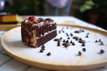 Close up a half piece of chocolate cake in a wooden dish on the table.