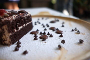 Close up a half piece of chocolate cake in a wooden dish on the table.