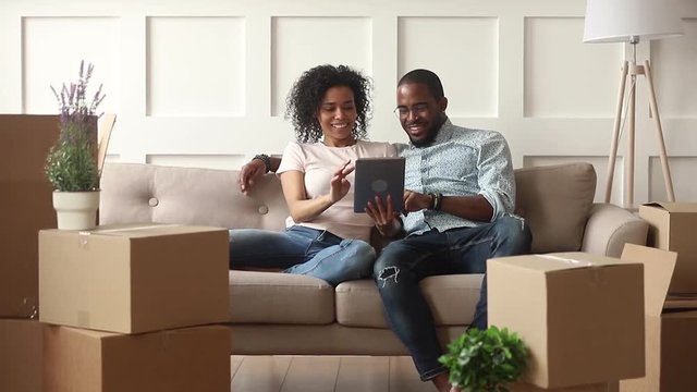 Happy african couple use digital tablet on moving day