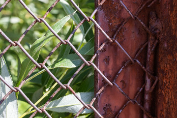 Rows of wire mesh and rusty metal pillar of fence. Wire mesh grid texture. Grunge backdrop. Rustic...
